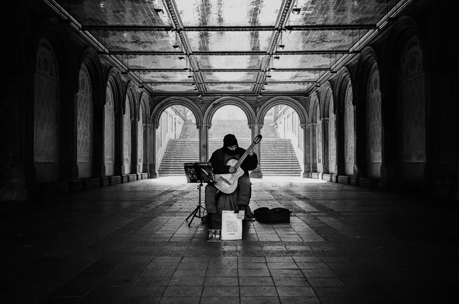 a guitarist playing alone under the arches of bethesda terrace, central park