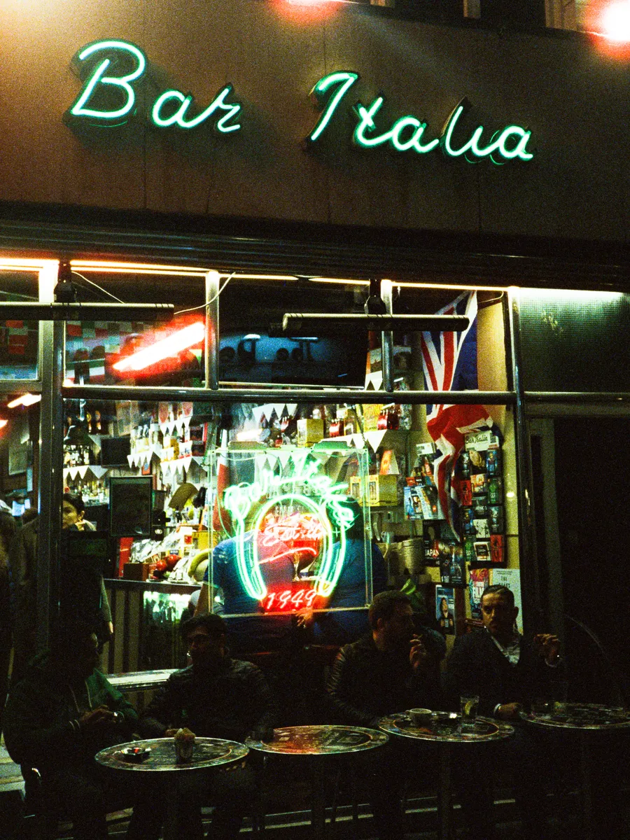bar italia's green neon sign above late-night tables, soho, london
