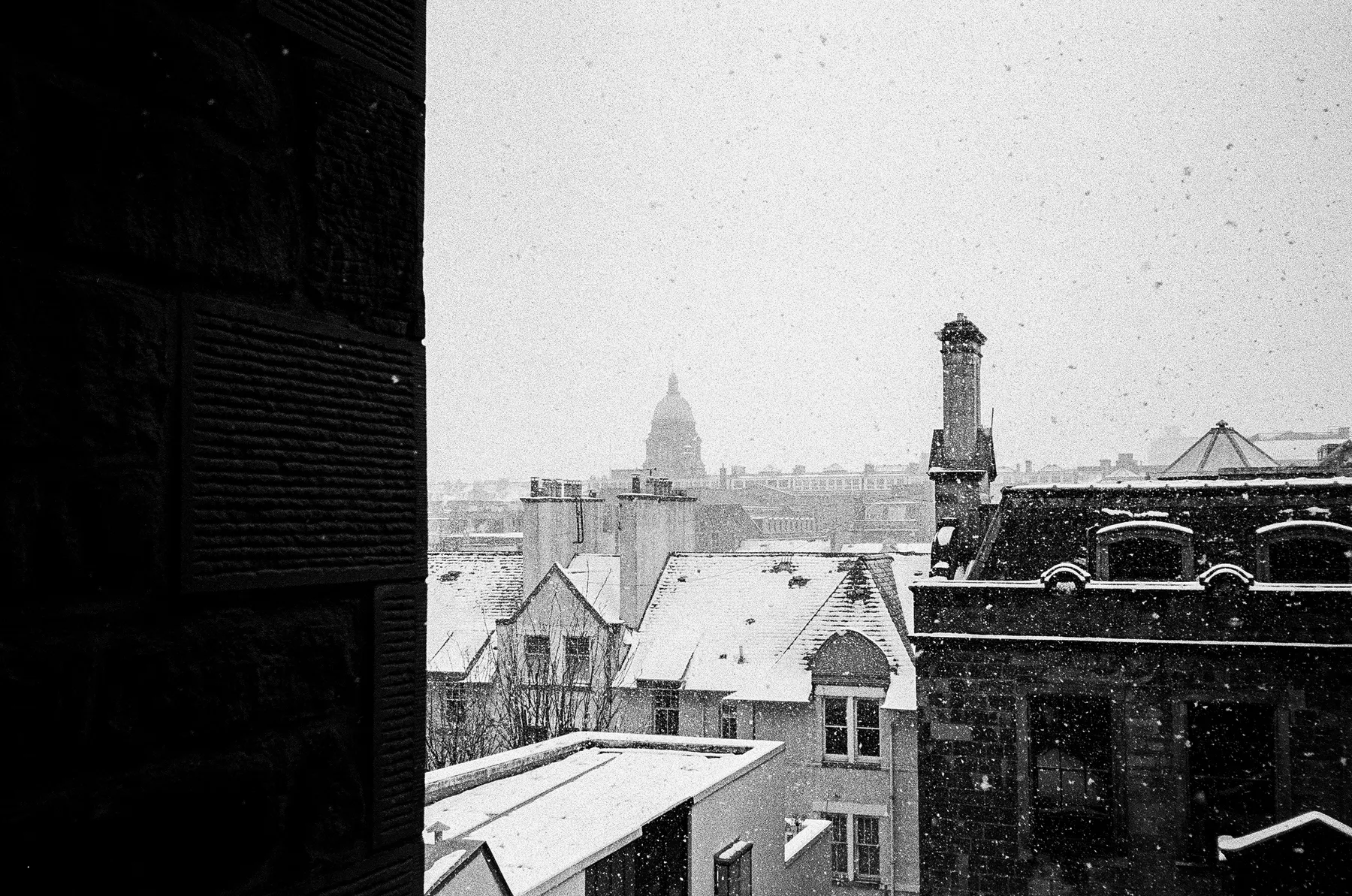 snow falling over the rooftops of old college, seen from a window, edinburgh