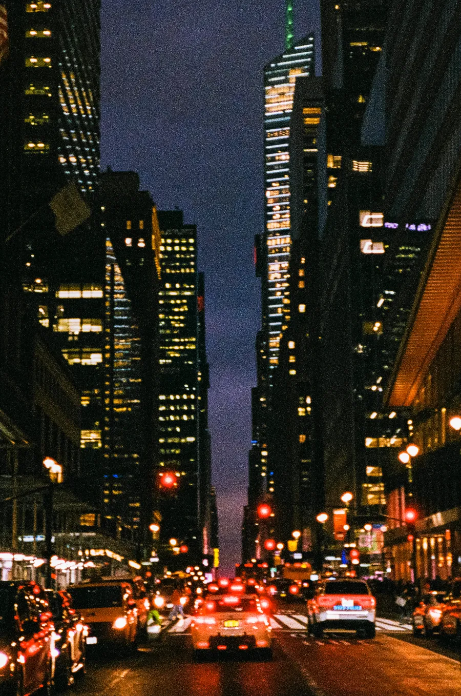 taillights and streetlights down a midtown canyon at dusk, new york